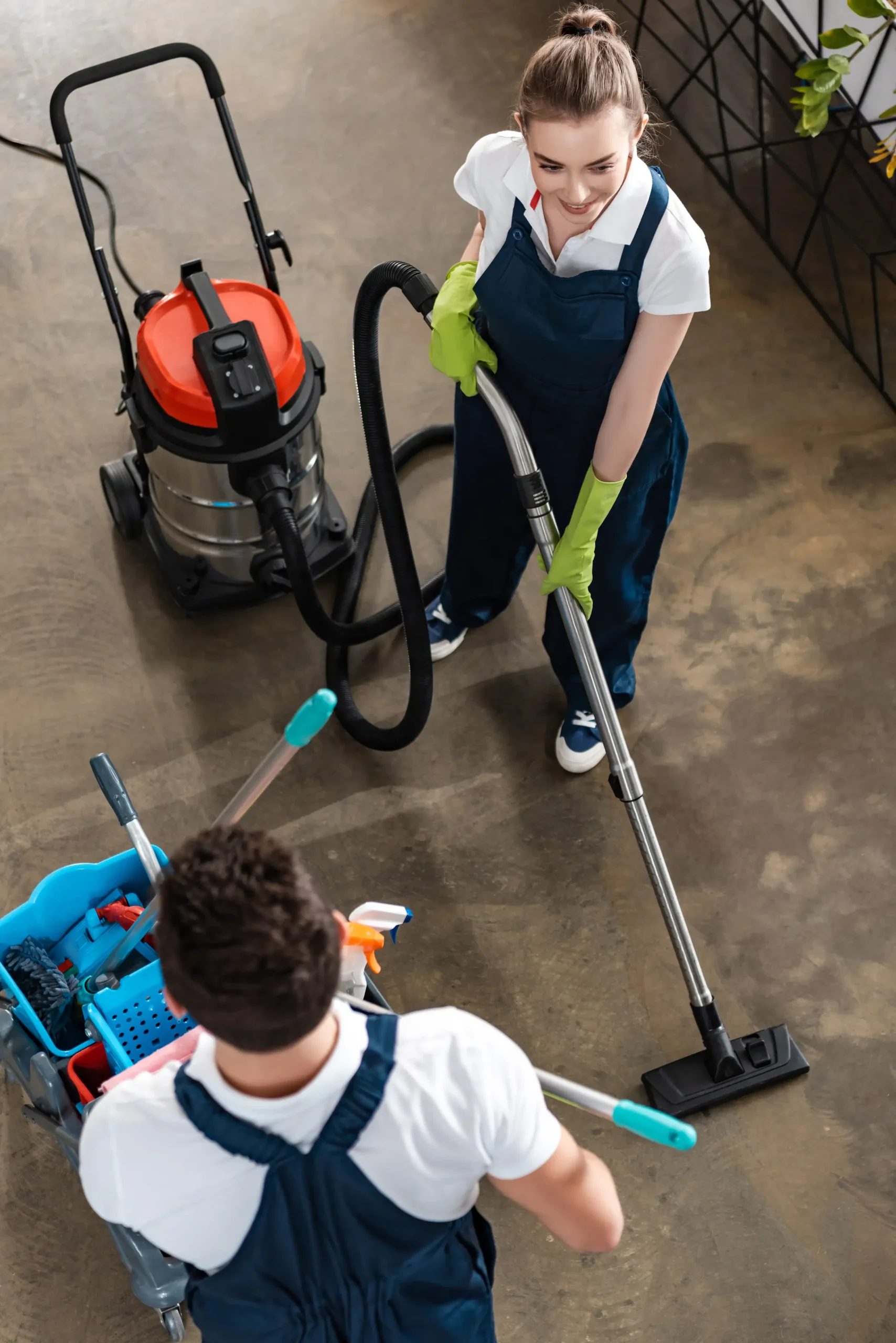 Two cleaning workers carefully vacuuming and sweeping the floor.