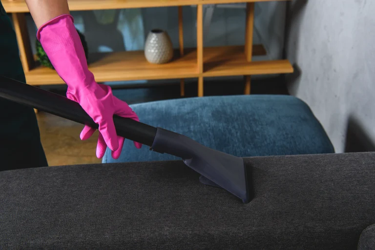A hand cleaning the sofa with a vacuum.